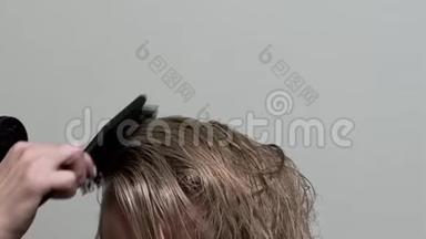 理发师用吹风机和毛刷擦干金发。